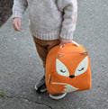 Small child holding a cute fox backpack.