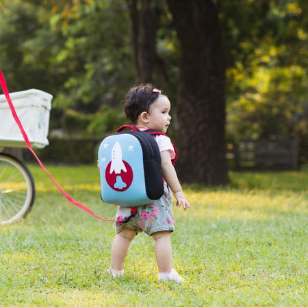 Toddler with Dabbawalla washable rocket harness bag.  Removable tether attaches to the bottom of the harness with a small hook.