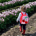 Little girl walking in tulips with a pink and red Dabbawalla toddler Harness Backpack