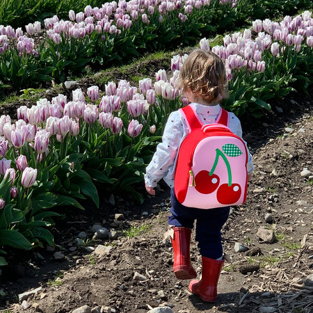 Toddler backpack by Dabbawalla Bags. Young girl wearing a red and pink Dabbawalla Cherry Harness Backpack.