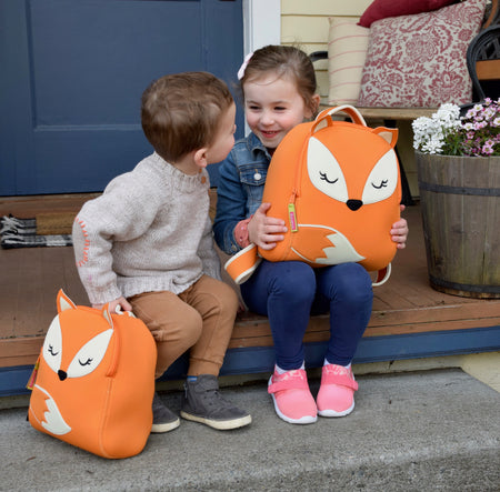 Big sister and brother holding their Fox backpacks.