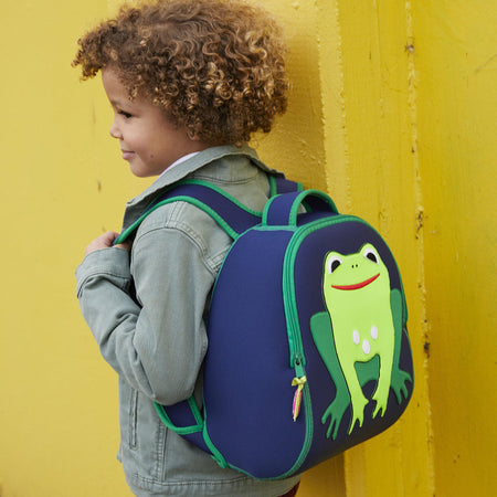 Young boy carrying the Dabbawalla Bags Frog backpack.  Bright green cute frog is stitched on the front of a navy preschooler backpack.