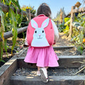 Young girl wearing the Bunny backpack walking up farm stairway