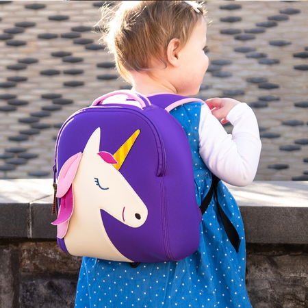 Cute little girl wearing a magical pink and purple Dabbawalla Unicorn harness backpack.