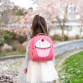 Girl wearing pink cupcake backpack made from sustainable material. eco-friendly and built to last.