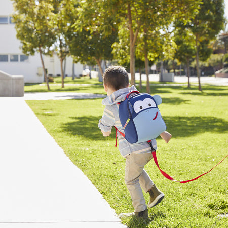 Boy running with a Dabbawalla Bags Harness Backpack and safety tether. Blue Monkey Harness Backpack by Dabbawalla Bags. Blue and red eco friendly material. 