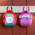 Apple and Pink Monkey lunch bags from Dabbawalla Bags. Bags are hanging from a cute horseshoe hook. 